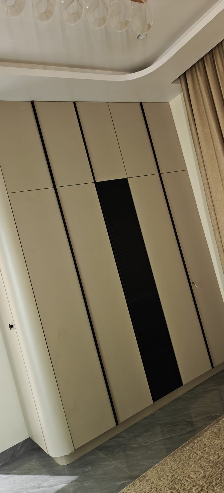 Floor to ceiling modular wardrobe with curved edge profile in a bedroom, Udgir