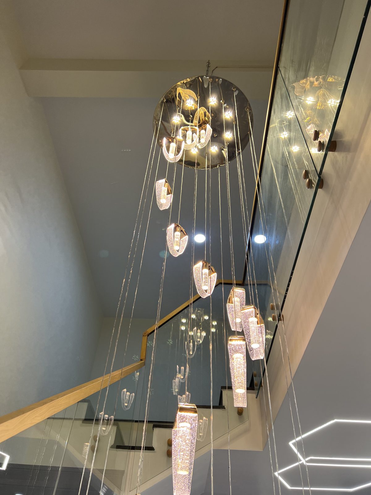 Double height stairwell with a cascading crystal chandelier and glass balustrade, Udgir