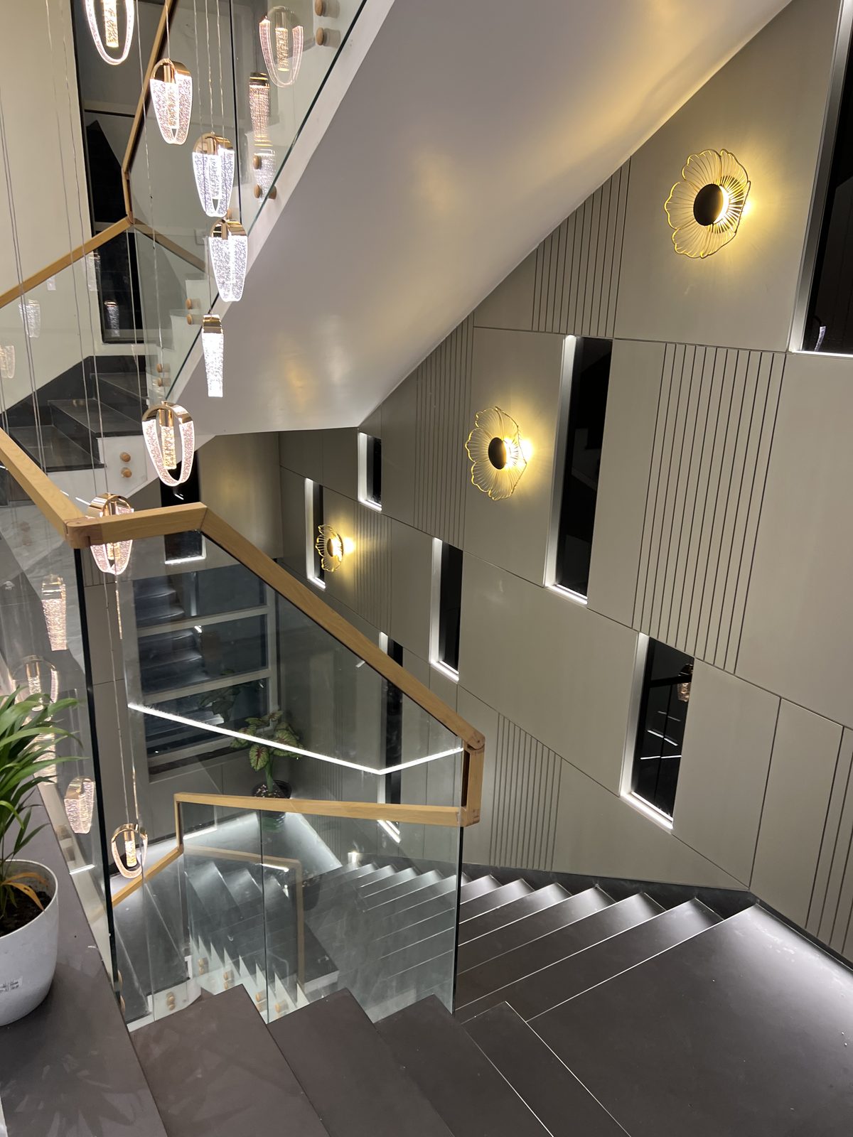 Modern staircase with glass railing, feature wall panelling and decorative wall lights, Latur