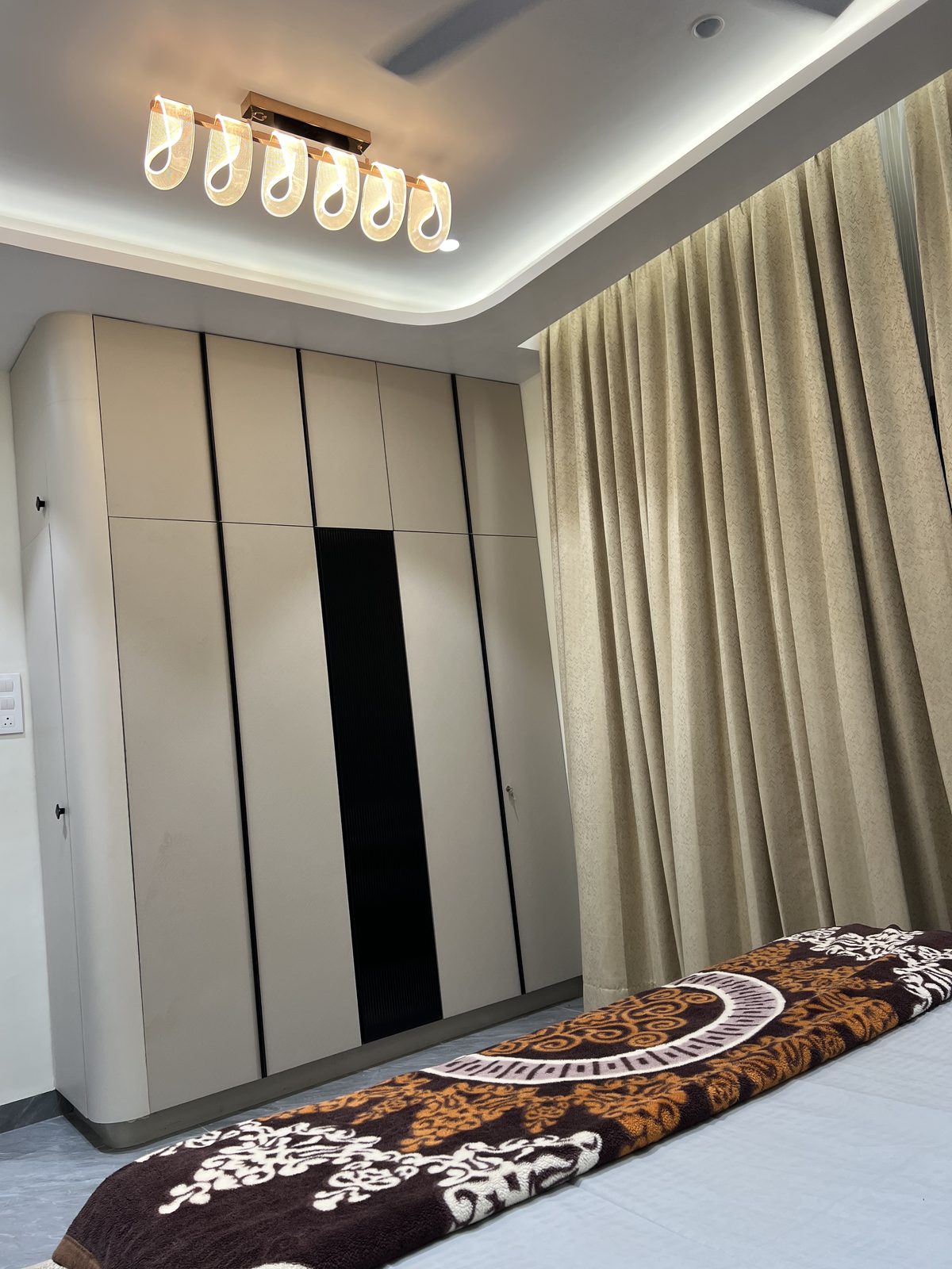 Modular wardrobe in cream laminate with handleless sliding doors and black inlay strip, Udgir