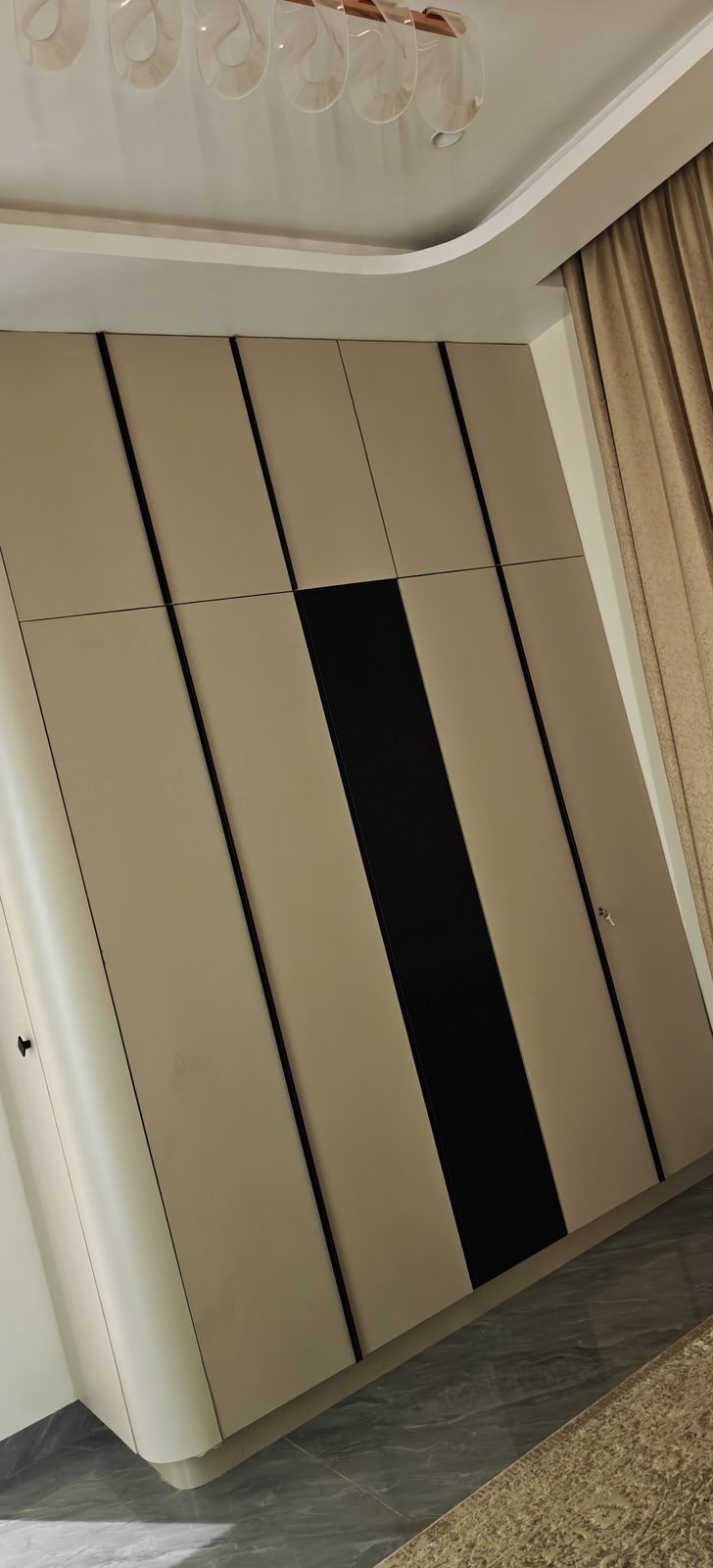 Floor to ceiling sliding wardrobe in cream finish with a vertical black accent panel, Latur