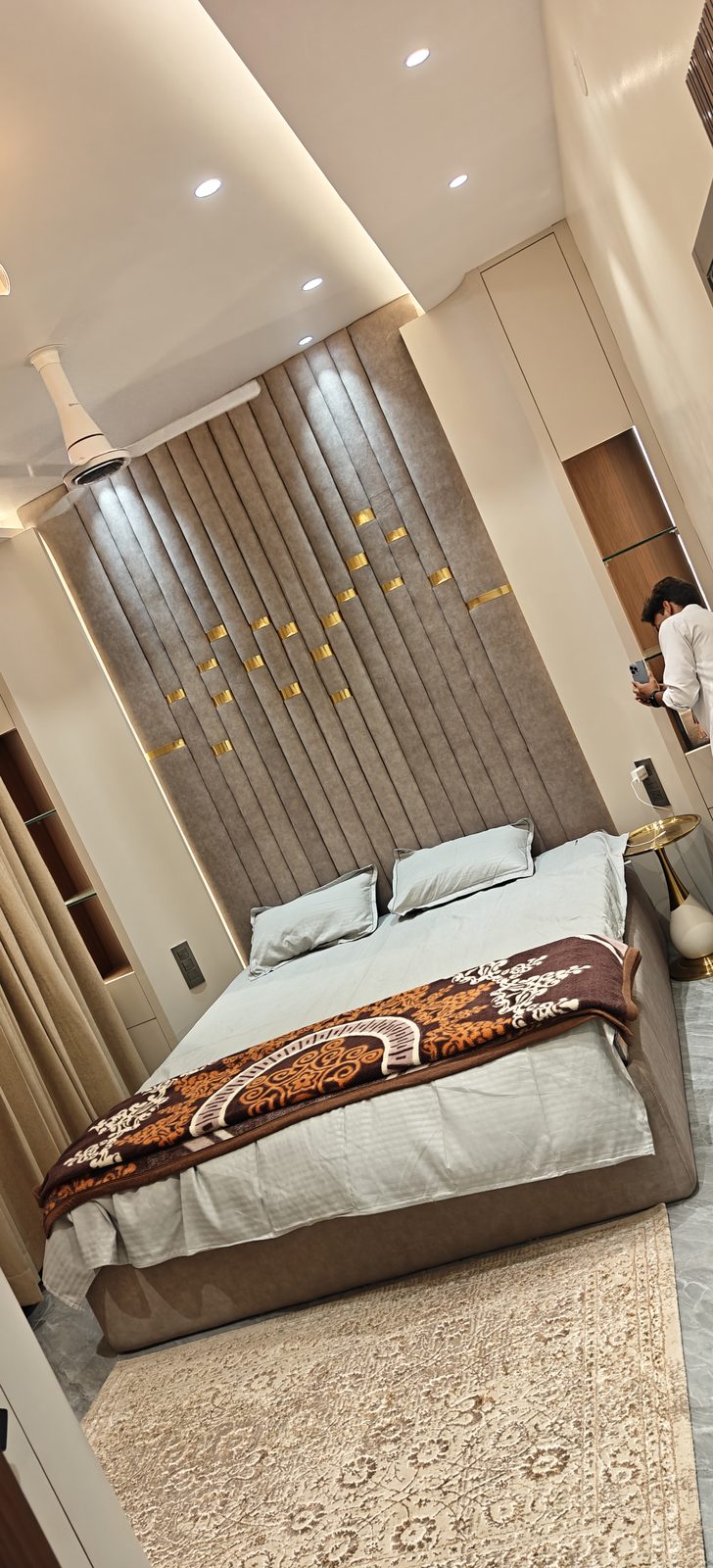Upholstered double bed against a panelled feature wall with recessed lighting, Udgir