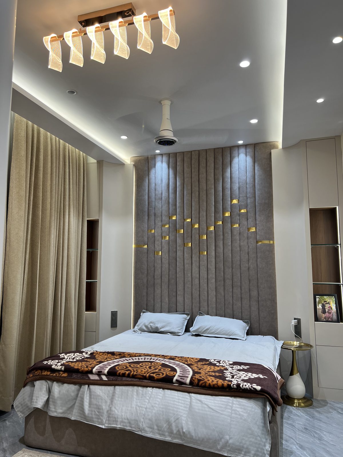 Upholstered king size bed with tall fluted headboard panel and gold accent lights, made by Shine Modular Furniture in Udgir